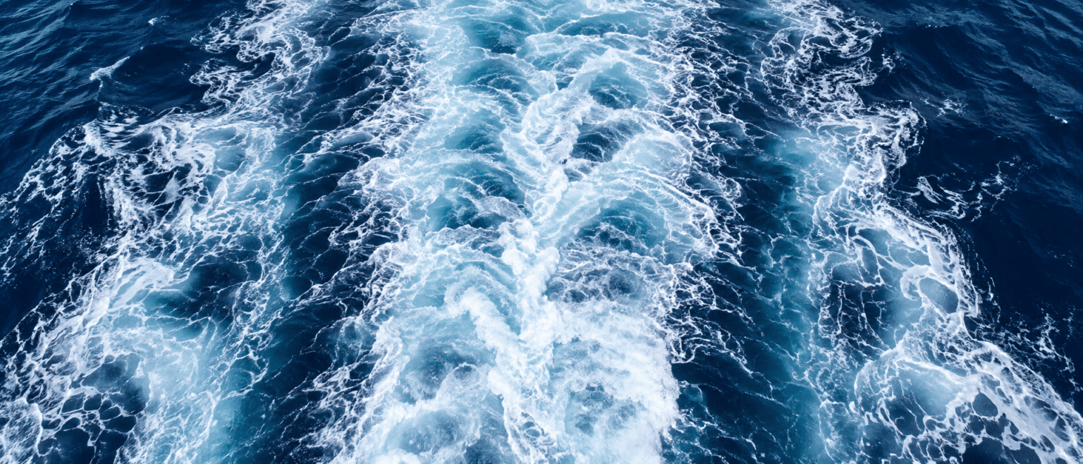 Churning white wake of a ship on deep blue water